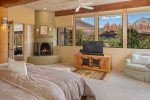 A luxurious bedroom with a kiva fireplace, flat screen TV and more red rock views from your pillow